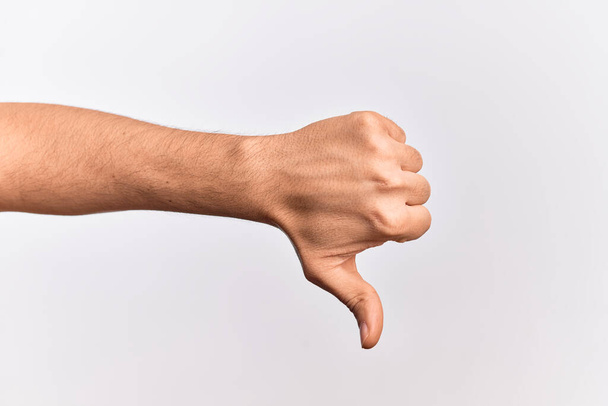 Dłoń białego młodzieńca pokazuje palce na białym tle robiąc kciuki w dół gest odrzucenia, dezaprobaty niechęć i negatywny znak - Zdjęcie, obraz