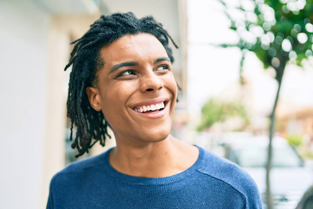 Jeune homme afro-américain souriant heureux regardant du côté de la rue de la ville. - Photo, image