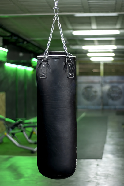 Vertikales Foto einer schwarzen Boxtasche in einem Fitnessstudio - Foto, Bild