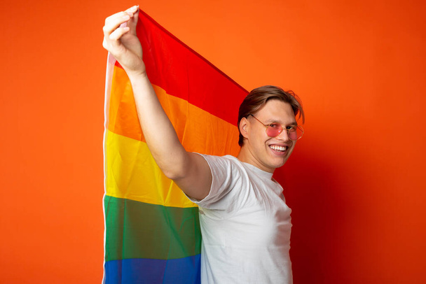 handsome young man with lgbt flag on red background - Foto, Imagen