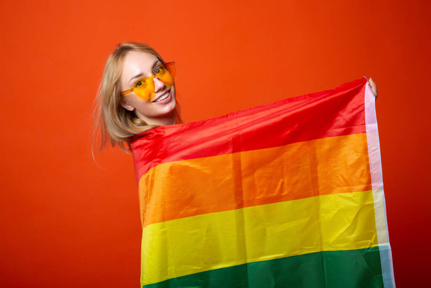 beautiful young woman with lgbt flag on red background - Фото, изображение