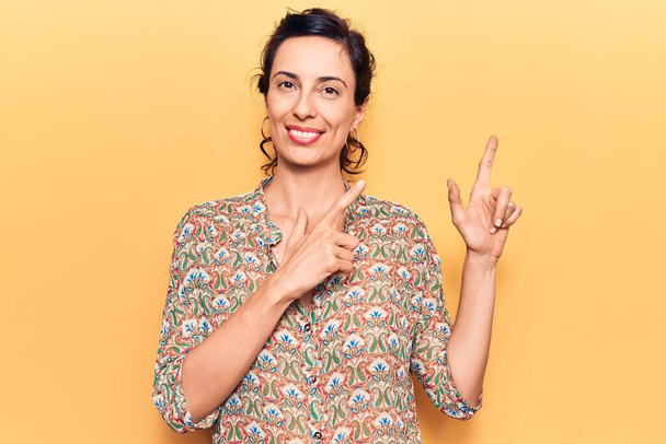 Young beautiful hispanic woman wearing casual clothes smiling and looking at the camera pointing with two hands and fingers to the side.  - Photo, image