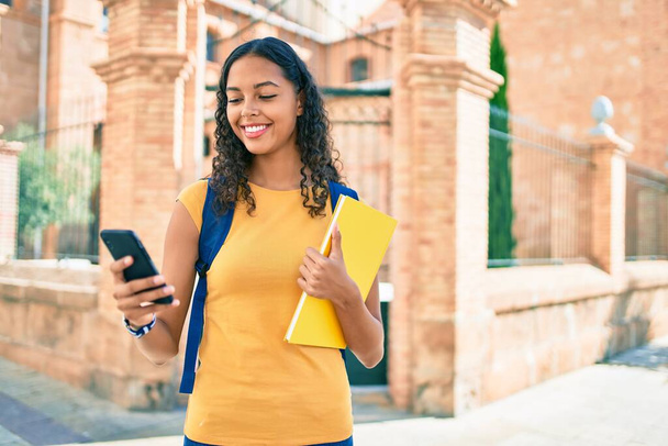 Молода афроамериканська студентка, яка користується смартфоном в університетському містечку.. - Фото, зображення