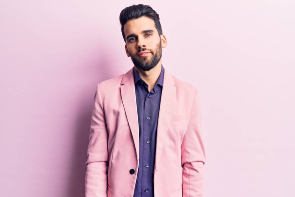 Young handsome man with beard wearing elegant jacket relaxed with serious expression on face. simple and natural looking at the camera.  - Zdjęcie, obraz