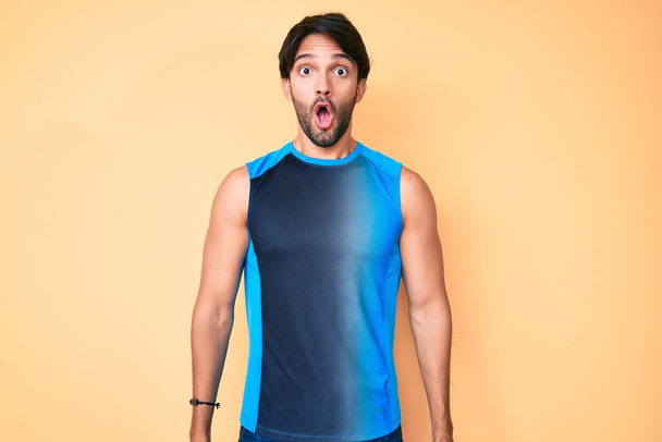 Handsome hispanic man wearing sportswear scared and amazed with open mouth for surprise, disbelief face  - Photo, Image