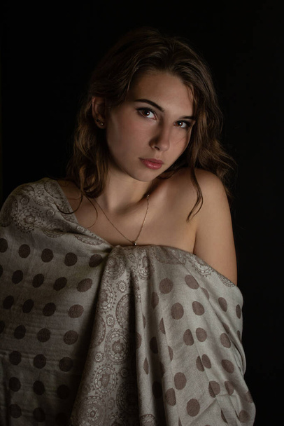 Retrato de una hermosa chica solitaria con el pelo rizado aislado sobre un fondo oscuro en la toma de estudio. - Foto, imagen