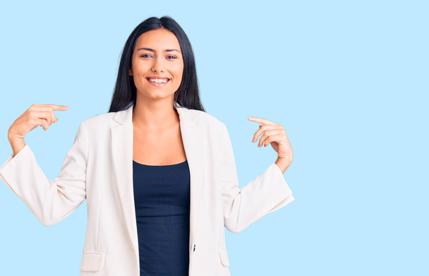 Young beautiful latin girl wearing business clothes looking confident with smile on face, pointing oneself with fingers proud and happy.  - Photo, Image