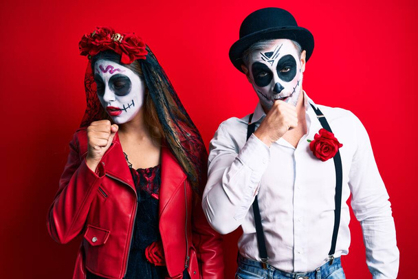 Couple wearing day of the dead costume over red feeling unwell and coughing as symptom for cold or bronchitis. health care concept.  - Photo, Image