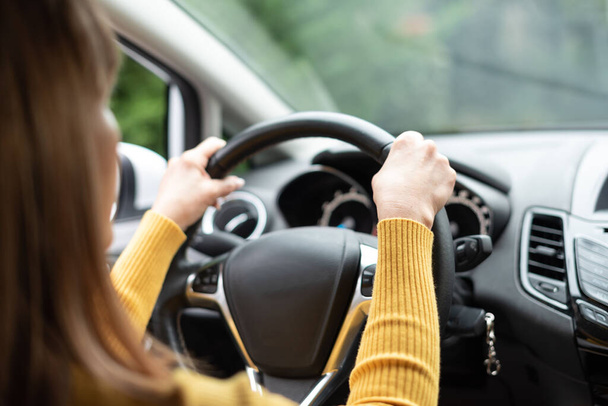 Kobieta prowadząca z dwiema rękami na kierownicy - Zdjęcie, obraz