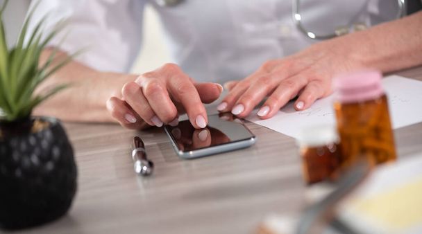 Médica usando seu telefone celular no consultório clínico - Foto, Imagem