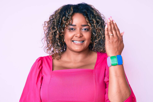 Young african american plus size woman wearing engagement ring looking positive and happy standing and smiling with a confident smile showing teeth  - Foto, afbeelding