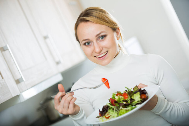Happy girl with vegetable salad in kitchen - 写真・画像