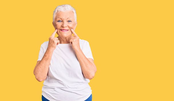 Senior krásná žena s modrýma očima a šedé vlasy na sobě ležérní bílé tričko s úsměvem s otevřenými ústy, prsty ukazuje a nutí veselý úsměv  - Fotografie, Obrázek