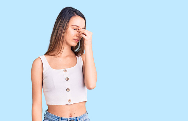 Young beautiful girl wearing casual sleeveless t shirt tired rubbing nose and eyes feeling fatigue and headache. stress and frustration concept.  - Photo, Image