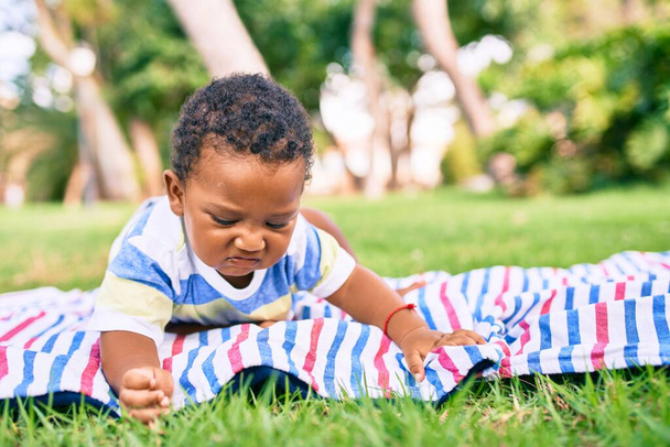 Adorable african american chubby toddler sitting on the grass at the park. - Foto, imagen