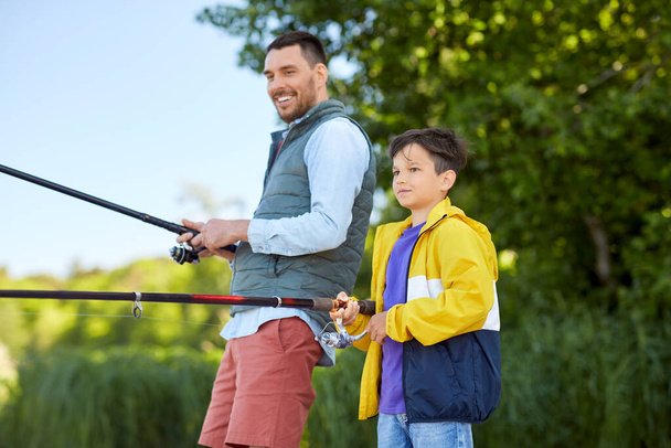 happy smiling father and son fishing on river - Foto, Imagem