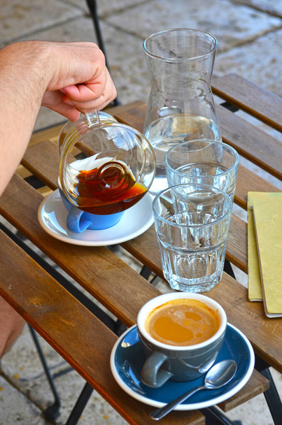 Férfi kéz öntő szűrő kávé és espresso lungo kék csésze kancsó vízzel egy fa asztal szabadban - Fotó, kép