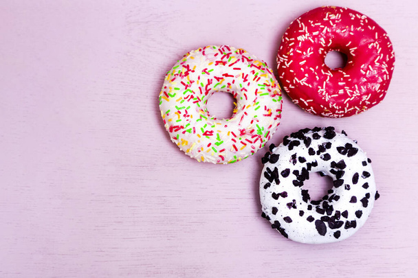 Donuts met glazuur op pastelroze achtergrond. Zoete donuts. Snoepjes op roze achtergrond. Een invloedrijke foto. Voedselconcept met kopieerruimte. - Foto, afbeelding