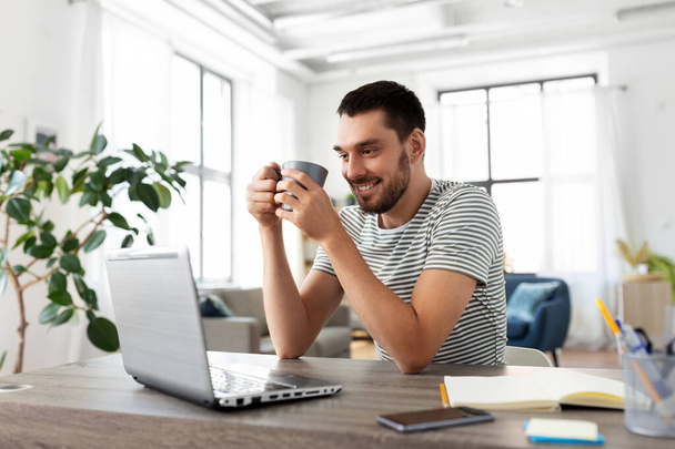 mężczyzna z laptopem pijący kawę w biurze - Zdjęcie, obraz