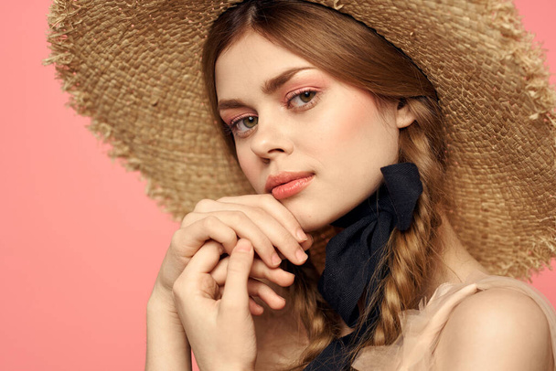 Retrato de uma menina em um chapéu de palha em um fundo rosa emoções close-up bela cara modelo tranças - Foto, Imagem