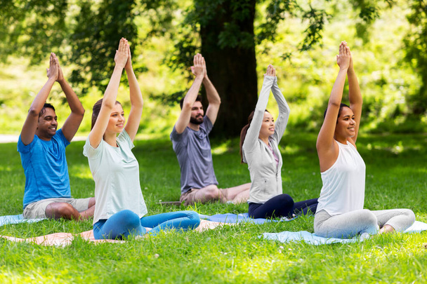 group of happy people doing yoga at summer park - Photo, image