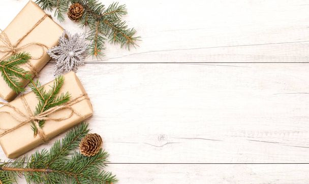 Christmas background and wallpaper. Happy New Year composition. Christmas gift, pine cones, fir branches on wooden white flat. Top view and copy space - Foto, afbeelding