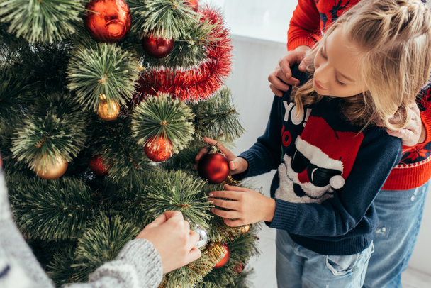 happy girl decorating christmas tree with parents at home  - Photo, Image