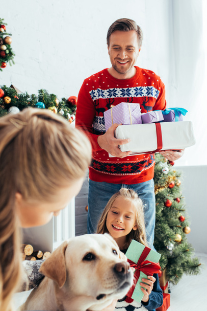 woman cuddling dog near kid and husband with gifts on christmas  - Photo, Image
