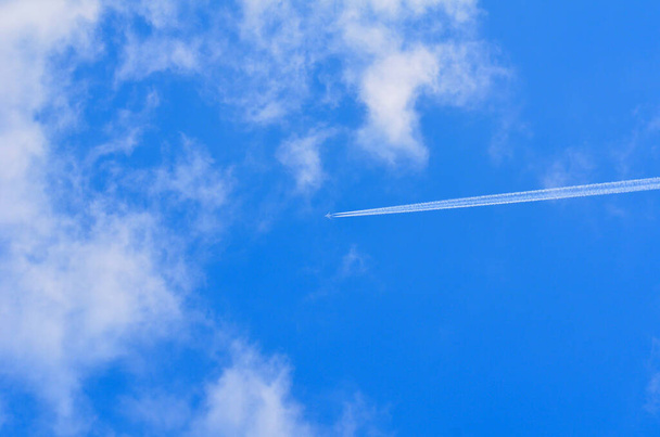 Flugzeug über den Wolken am blauen Himmel mit Kondensstreifen - Foto, Bild