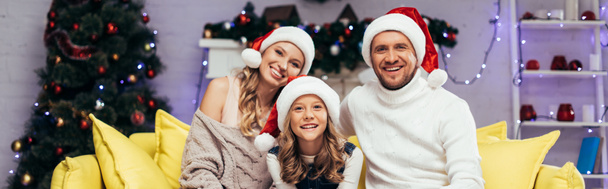 happy family in santa hats looking at camera in decorated living room, banner - Φωτογραφία, εικόνα