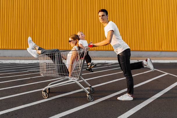 Excited happy family having fun ride on shopping cart outdoors, family shopping concept - 写真・画像