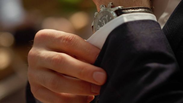 Reicher Mann knöpft Hemdsärmel unter Bogen zu. Männerhände mit Armbanduhr - Foto, Bild