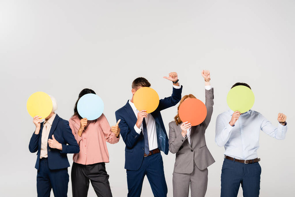 Багатокультурні бізнесмени показують, як жест, покриваючи обличчя картами, ізольованими на сірому
 - Фото, зображення
