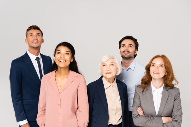 Empresários multiculturais sorridentes olhando para cima isolados em cinza - Foto, Imagem