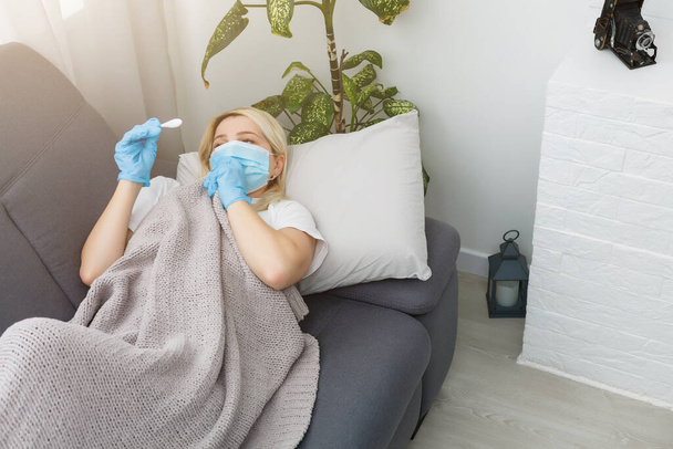 Vrouw in bed in het gezicht masker. Coronavirus COVID-19-concept. - Foto, afbeelding