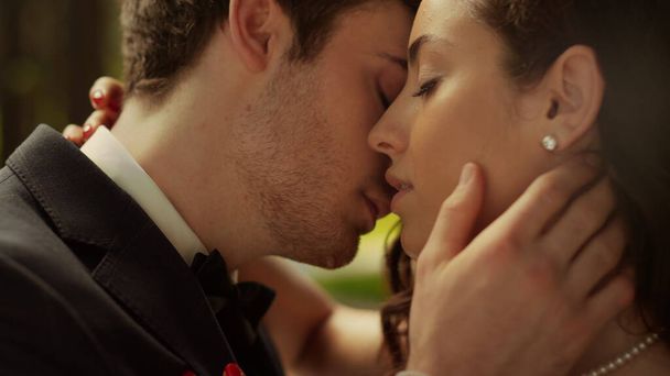 外で女の頬にキスするハンサムな男。公園での官能的なカップルのポーズ - 写真・画像