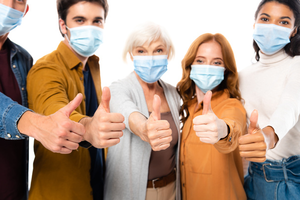 Multiethnic people showing like while wearing medical masks on blurred background isolated on white - Foto, imagen