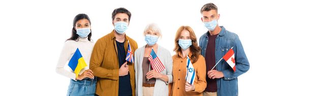 personnes multiethniques dans des masques médicaux tenant des drapeaux isolés sur blanc, bannière  - Photo, image