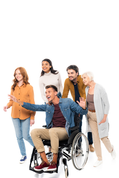 Smiling multiethnic friends walking near man in wheelchair on white background  - Photo, Image