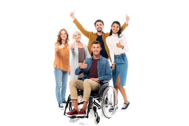 Smiling multiethnic people showing like near man in wheelchair on white background  - Фото, зображення