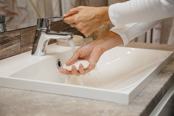 Η γυναίκα πλένει τα χέρια της με σαπούνι στο μπάνιο. - Φωτογραφία, εικόνα