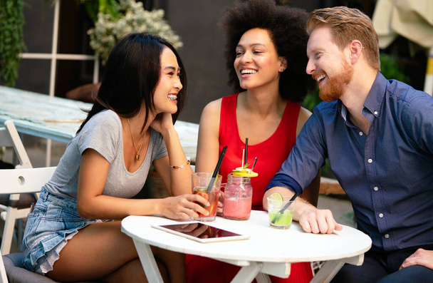 Diverso grupo de amigos felices divirtiéndose, hablando, sonriendo en la cafetería al aire libre en verano - Foto, imagen