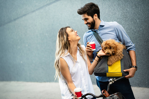 Laughing young couple with small dog walking, talking in the city - Foto, Imagen