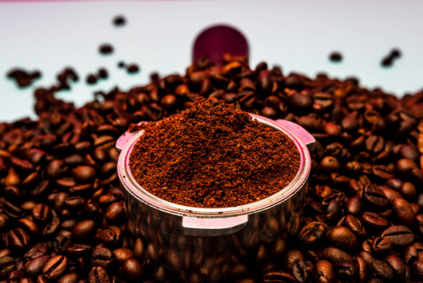 Background with ground coffee in portafilter surrounded by roasted coffee beans, - Photo, Image