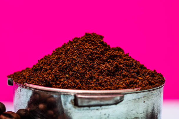 Close-up van portafilter met gemalen koffie geïsoleerd op roze achtergrond - Foto, afbeelding