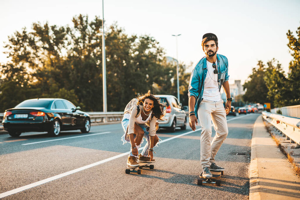 Красивая молодая пара наслаждается скейтбордингом на городской улице. - Фото, изображение