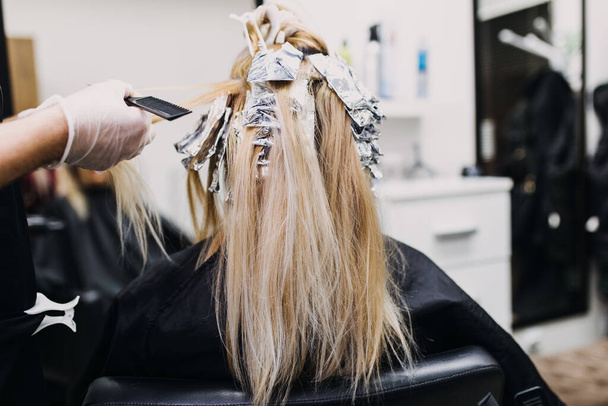 Парикмахер умирает женские волосы, делая прически для своего клиента с фольгой.  - Фото, изображение