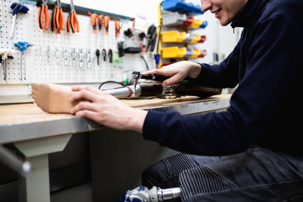 Hombre discapacitado que trabaja en una tienda de amputados para la producción de piezas de prótesis para extremidades. - Foto, Imagen