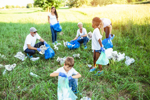 Vapaaehtoiset roskapussien kanssa siivoamassa roskia ulkona - ekologia. - Valokuva, kuva