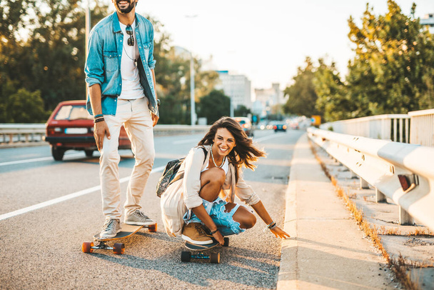Piękna młoda para korzystających skateboarding na ulicy miasta. - Zdjęcie, obraz